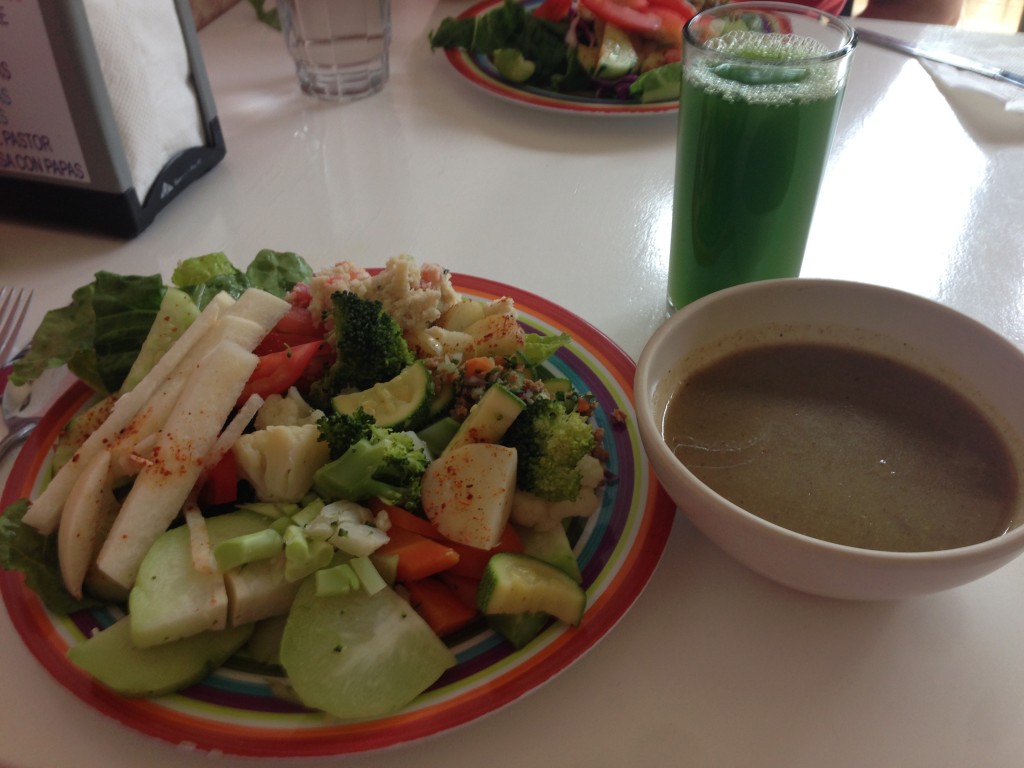 A mixed salad with fresh Romaine lettuces, tomatoes, cucumbers, Jicama, steam chayote (squash), steamed broccoli, and steamed cauliflower, a side of mushroom veggie soup and a power-green juice with celery, parsley and cactus juice.